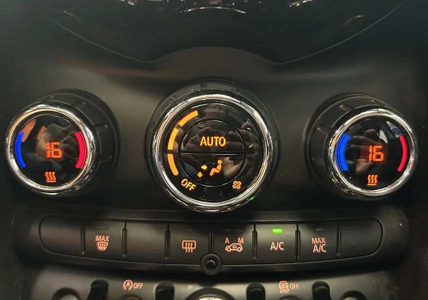 Gros plan sur les commandes de climatisation automatique avec affichage digital orange dans une MINI 5P bleu de 2015.