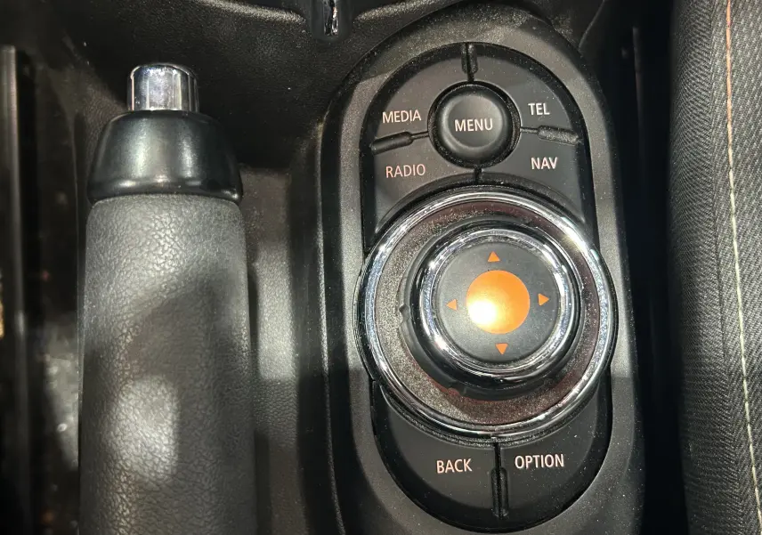 Gros plan sur la molette de commande centrale noire et chrome avec levier de frein à main en cuir noir dans une MINI 5P Cooper D 2015.