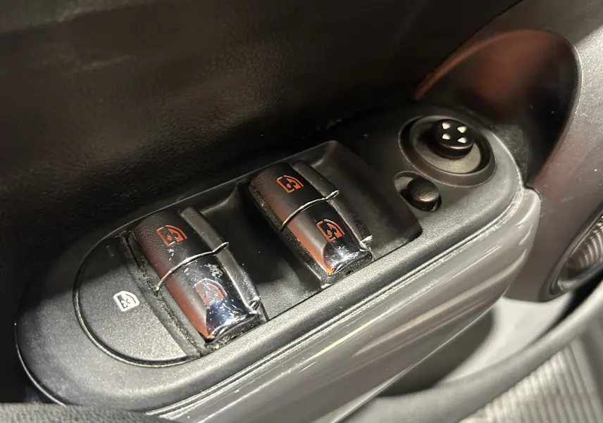Gros plan sur les commandes électriques des vitres côté conducteur d’une MINI 5 portes bleu, version Cooper D 2015.