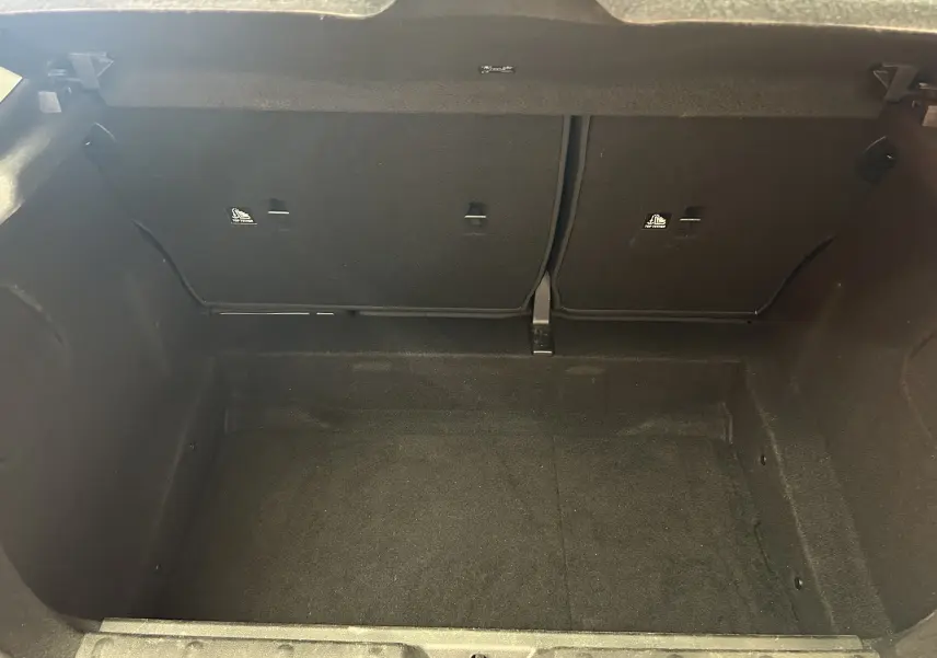 Coffre ouvert en vue plongeante d'une MINI 5 portes, intérieur noir avec banquette arrière rabattue partiellement visible.