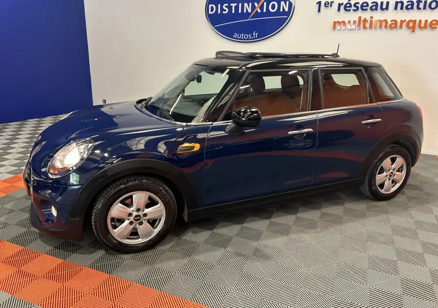 Vue latérale droite d'une MINI 5 portes Cooper D bleu avec toit ouvrant et jantes alliage, stationnée en intérieur.