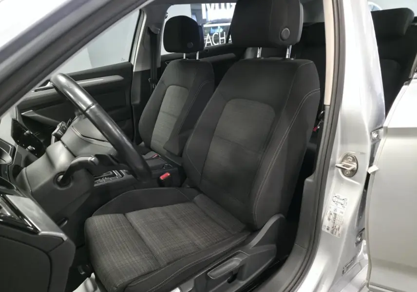 Vue intérieure côté conducteur de la Volkswagen Passat SW 2021 gris, sièges tissu noir et console centrale visible.