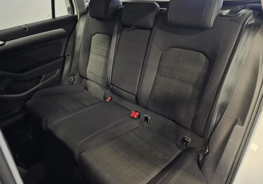 Vue intérieure côté arrière droit de la banquette tissu gris foncé avec appuie-têtes et ceintures de sécurité de la Volkswagen Passat SW 2021.