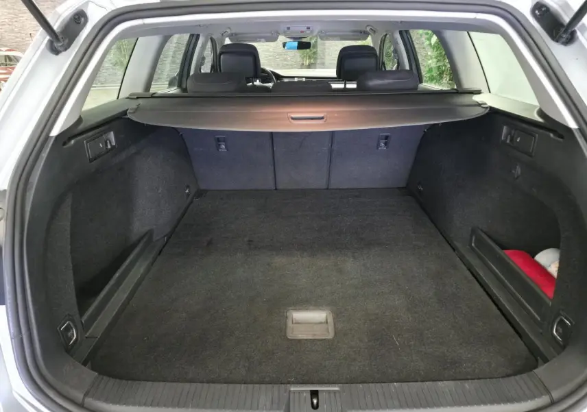 Coffre ouvert d’une Volkswagen Passat SW gris, vue arrière montrant l’espace de chargement et la plage arrière rétractable.