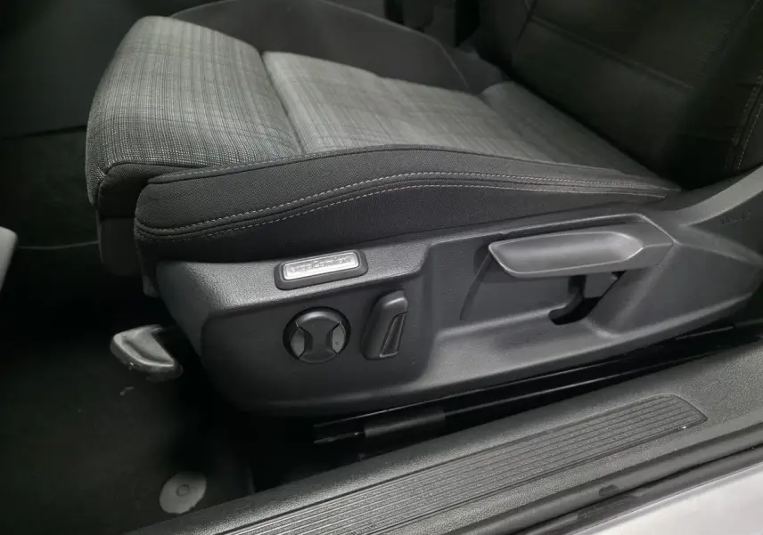 Gros plan sur le siège conducteur tissu gris et noir avec réglages manuels et étiquette "ErgoComfort" dans une Volkswagen Passat SW 2021.