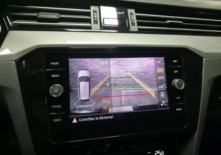 Écran tactile central affichant la caméra de recul et l'aide au stationnement de la Volkswagen Passat SW gris, vue intérieure.