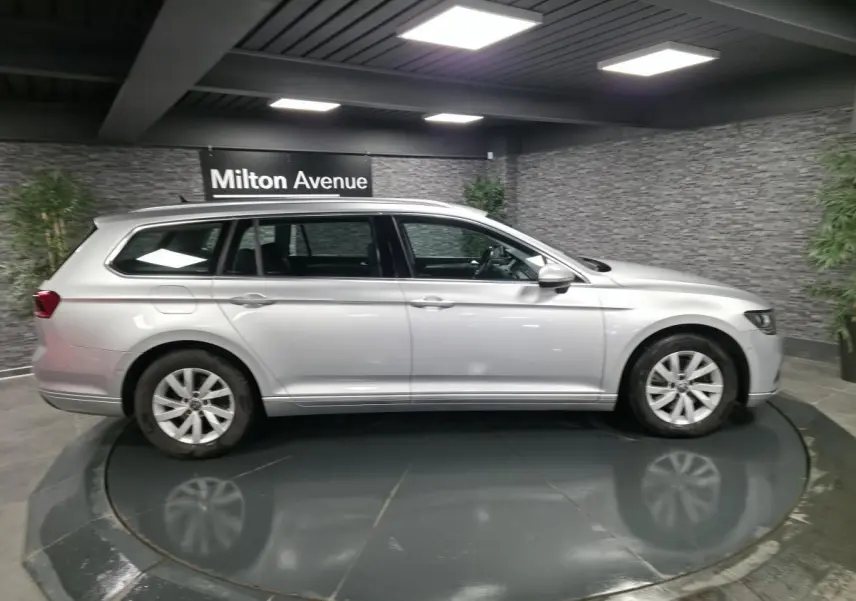 Volkswagen Passat SW gris métallisé vue de profil côté gauche dans un showroom intérieur sobre.