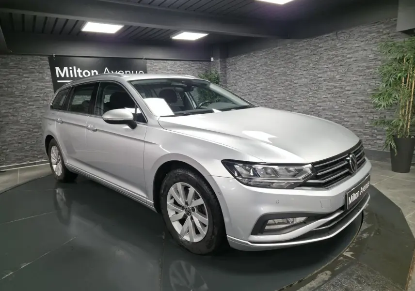 Volkswagen Passat SW gris métallisé vue 3/4 avant droit en intérieur avec jantes alliage et calandre chromée.