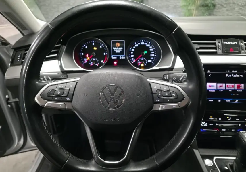 Vue intérieure centrée sur le volant cuir multifonction de la Volkswagen Passat SW 2021 avec tableau de bord et écran tactile.