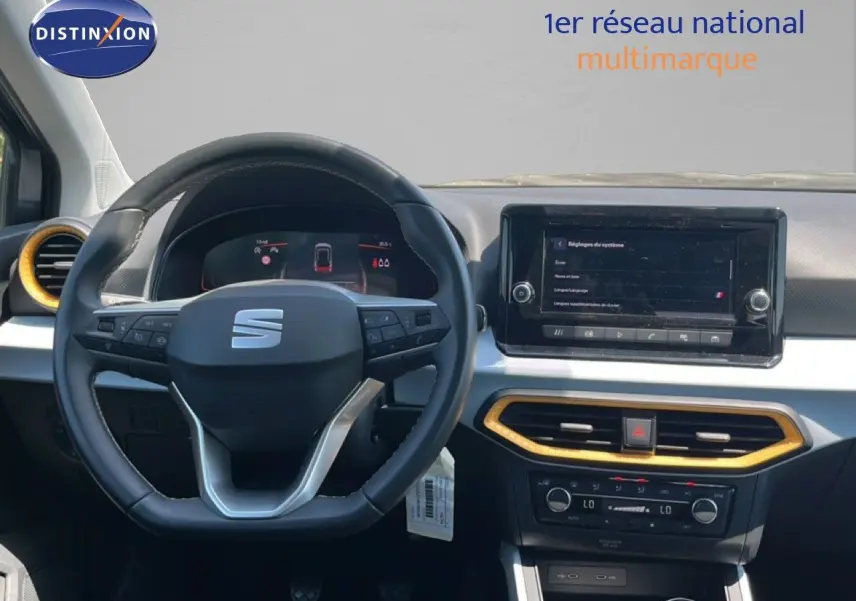 Vue frontale de l'intérieur du SEAT Arona gris, volant multifonctions et écran tactile avec cadre noir et garniture dorée.