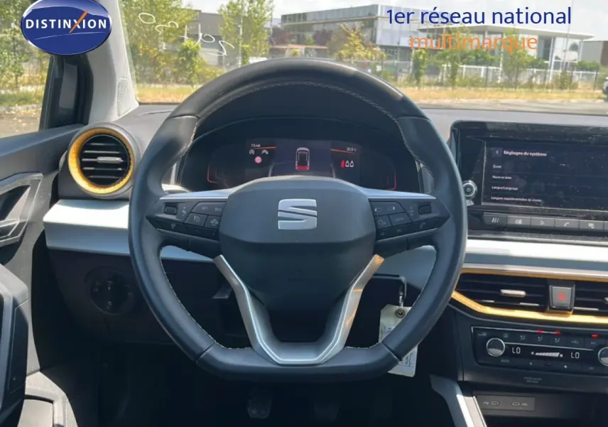 Vue intérieure centrée sur le volant noir du SEAT Arona 2026 avec détails gris et touches dorées autour des aérateurs.