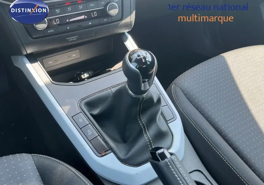 Gros plan sur la console centrale d’une SEAT Arona gris magnetic, avec levier de vitesse manuel et sièges tissu gris.