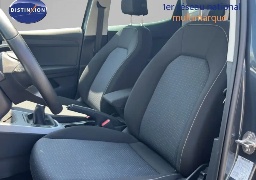 Vue intérieure côté conducteur du SEAT Arona gris magnetic avec sièges tissu gris et noir, volant multifonction et boîte manuelle.