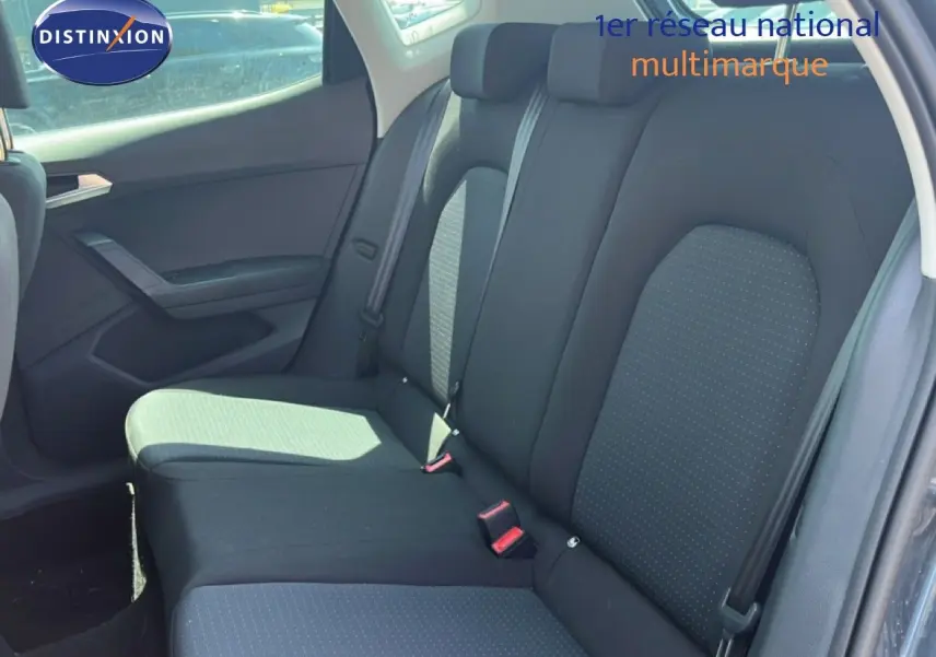 Vue latérale gauche de l’intérieur arrière du SEAT Arona 2026, sièges tissu gris foncé avec ceinture de sécurité.