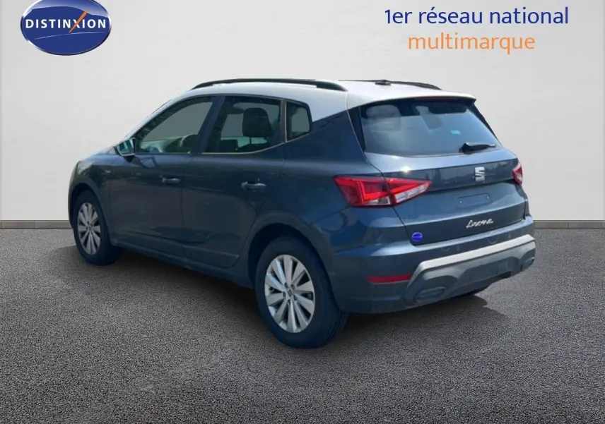 Vue 3/4 arrière gauche d'un SEAT Arona gris magnetic avec toit blanc, mettant en valeur ses feux arrière et jantes.