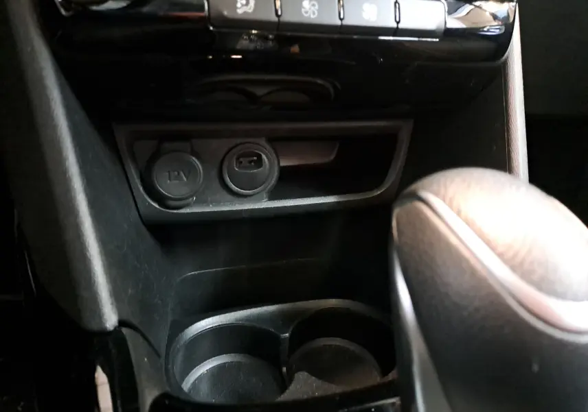 Gros plan sur la console centrale noire du Peugeot 2008 2019, montrant prises 12V et USB avec levier de vitesse en cuir.