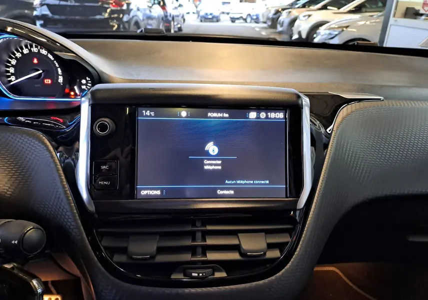 Vue rapprochée de l'écran tactile central et du tableau de bord noir d'un Peugeot 2008 gris 2019 en intérieur.