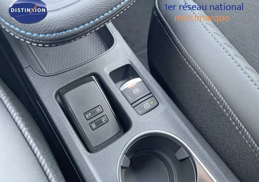 Gros plan sur la console centrale du Renault Symbioz gris Rafale, avec boutons de frein à main et porte-gobelet visible.