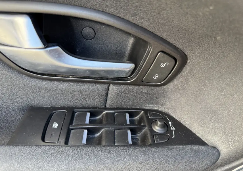 Gros plan sur la commande des vitres et la poignée intérieure côté gauche du Range Rover Evoque gris 2017.
