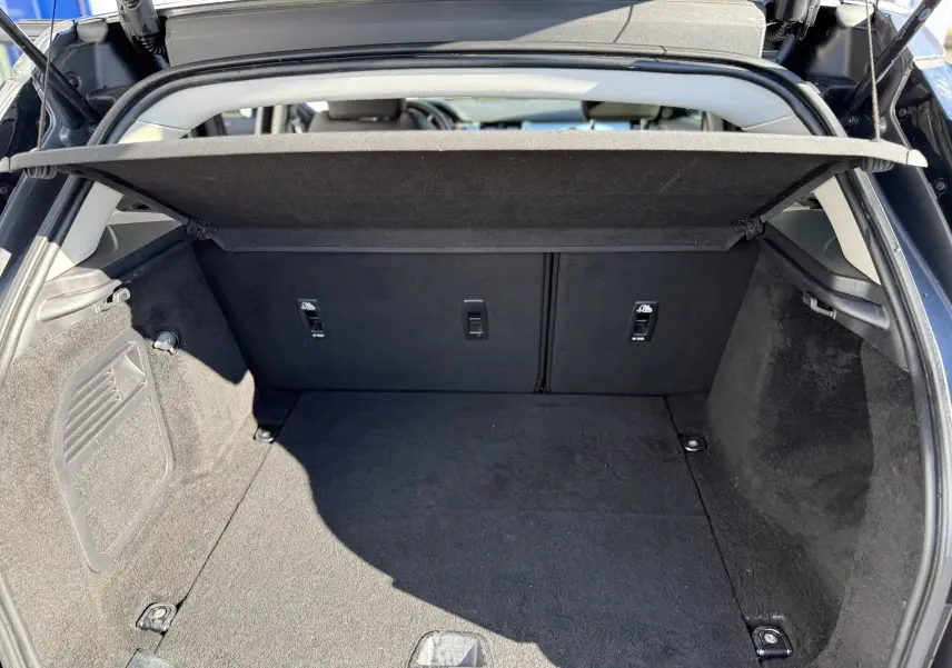 Vue intérieure du coffre ouvert d'un Range Rover Evoque gris, montrant un espace de rangement propre et bien fini.