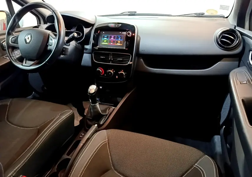 Vue intérieure avant droite de la Renault Clio blanche 2016, volant cuir multifonctions et écran tactile central.