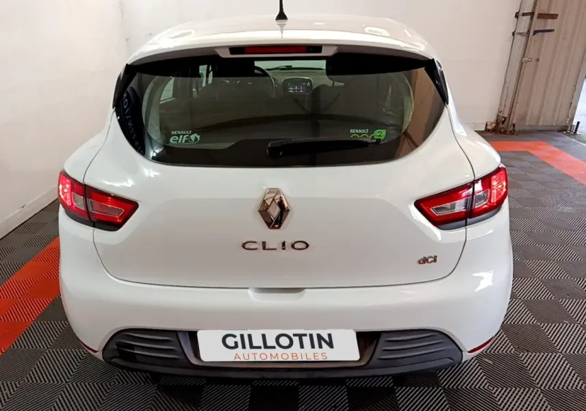 Vue arrière d'une Renault Clio Zen Energy dCi blanche de 2016 avec feux arrière allumés et logo visible.