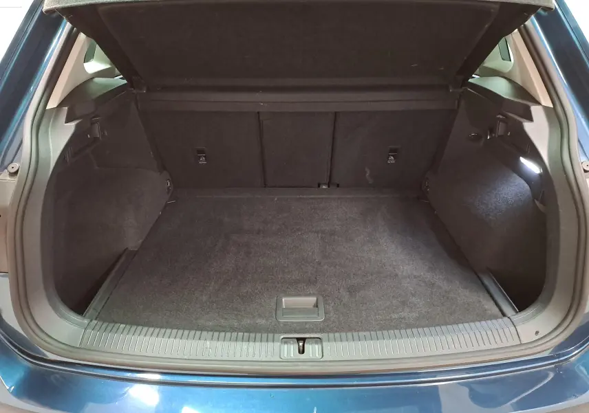 Coffre ouvert vu de l'arrière d'un Volkswagen Tiguan 2023 bleu Nightshade avec intérieur noir et tapis de coffre.