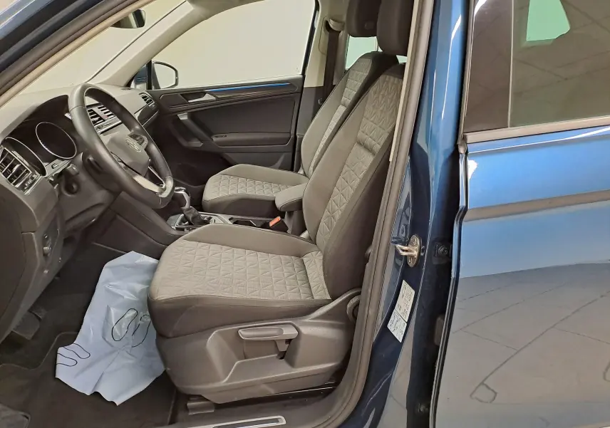 Vue intérieure côté conducteur du Volkswagen Tiguan 2023 bleu Nightshade avec sièges tissu gris à motifs géométriques.