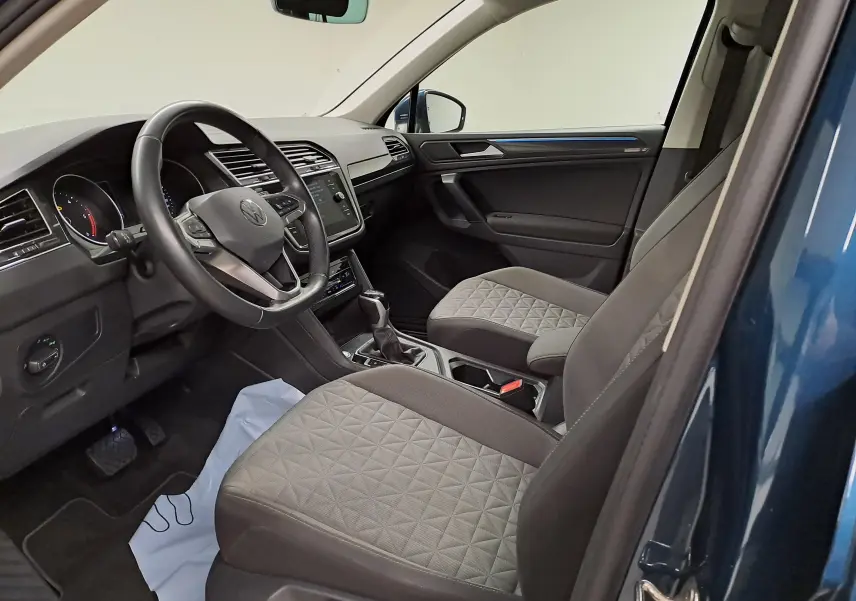 Vue intérieure côté conducteur du Volkswagen Tiguan 2023 bleu Nightshade, montrant sièges et tableau de bord modernes.