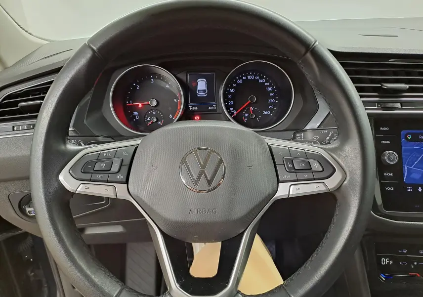 Vue rapprochée du volant multifonction noir du Volkswagen Tiguan 2023 avec tableau de bord et écran tactile visibles.