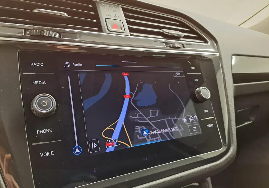 Vue rapprochée de l'écran tactile central du Volkswagen Tiguan 2023 avec navigation active, entouré de commandes noires.