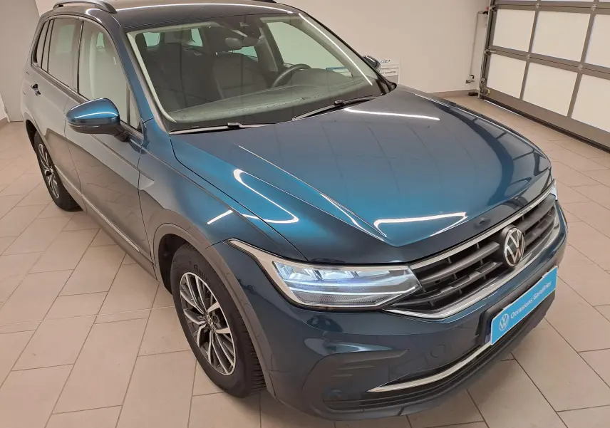Volkswagen Tiguan 2023 bleu Nightshade, vue 3/4 avant droit, jantes 17'' Tulsa et attelage escamotable visible.
