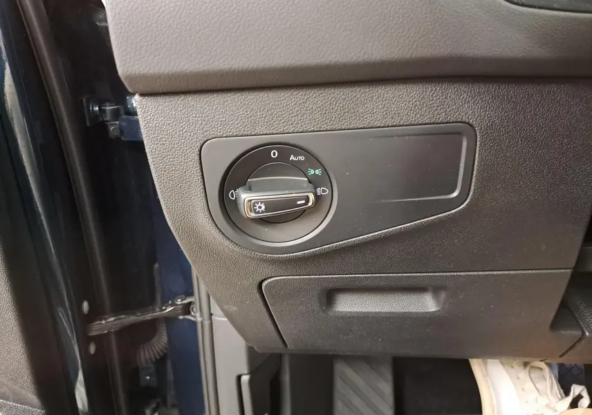 Gros plan sur le bouton de commande des phares côté gauche du tableau de bord du Volkswagen Tiguan Nightshade Blue 2023.