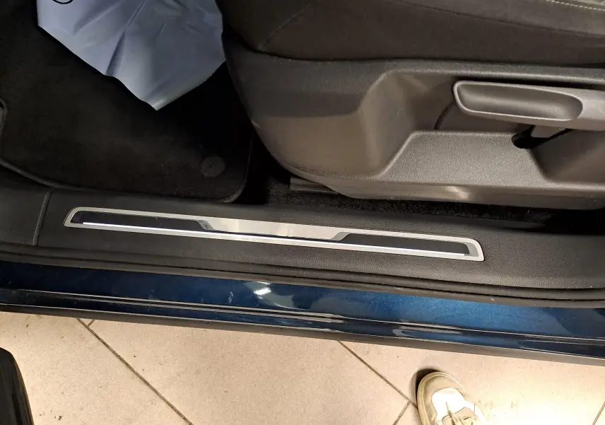 Détail de la partie basse côté gauche d’un Volkswagen Tiguan 2023 en Nightshade Blue avec seuil de porte et siège conducteur.