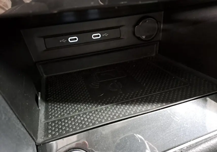 Gros plan sur la console centrale du Volkswagen Tiguan 2023 avec ports USB-C et surface de charge sans fil noire.