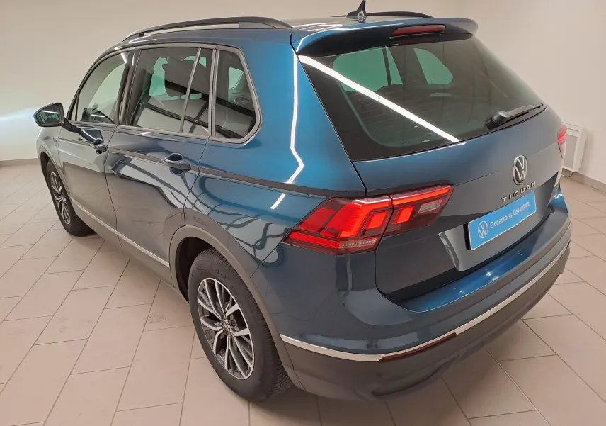 Vue 3/4 arrière droite du Volkswagen Tiguan 2023 en bleu Nightshade avec jantes 17'' Tulsa et attelage escamotable visible.