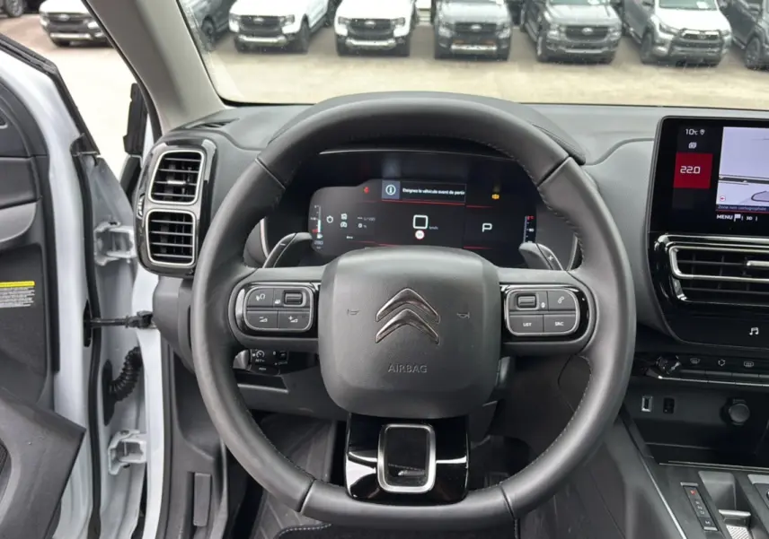 Vue intérieure centrée sur le volant cuir multifonctions du Citroën C5 Aircross blanc, avec tableau de bord digital et écran tactile.