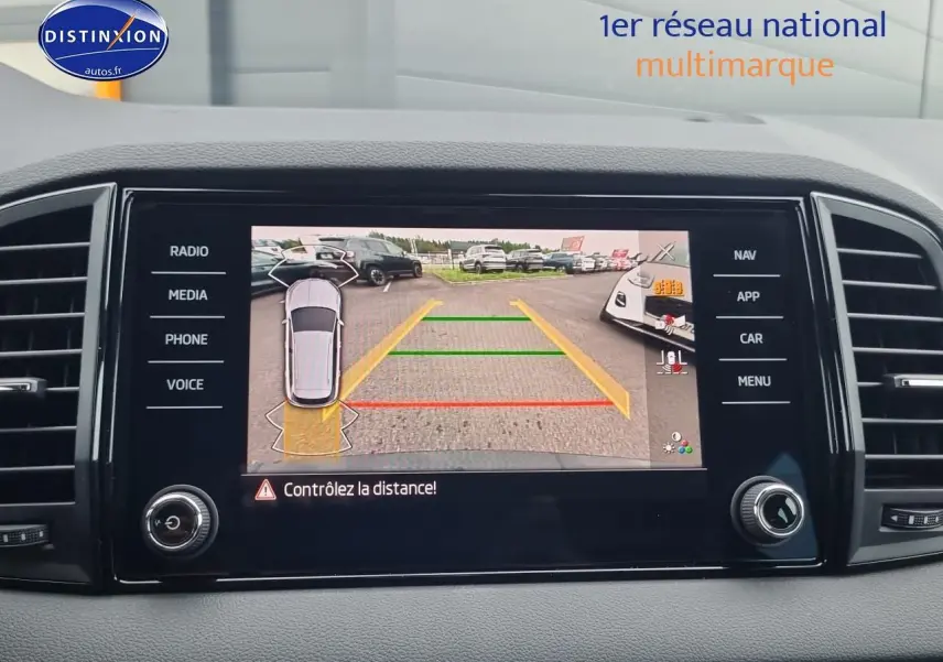 Écran tactile intérieur montrant la caméra de recul avec lignes de guidage du Skoda Karoq noir, vue du tableau de bord.