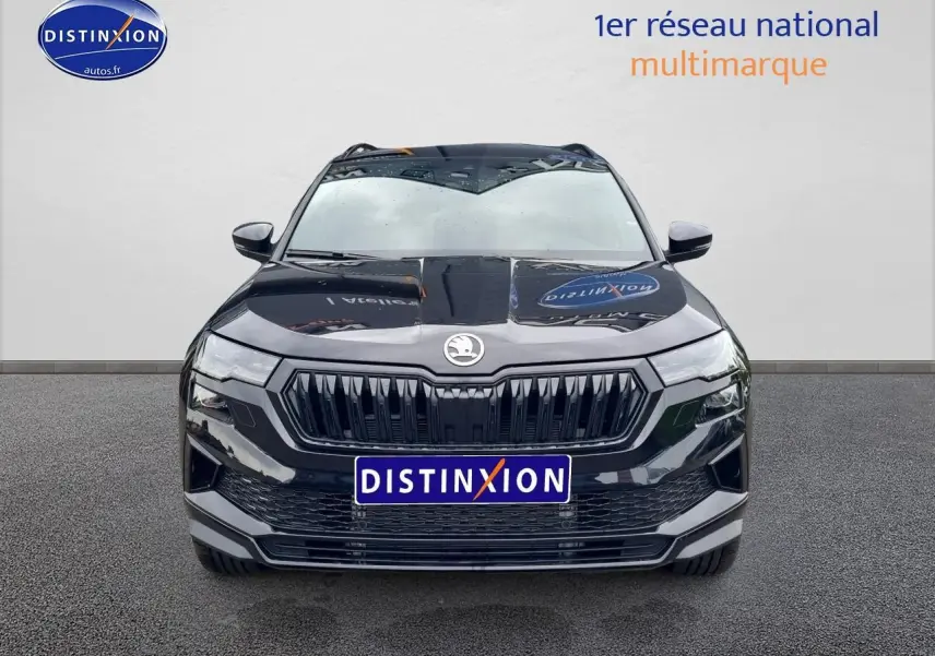 Vue avant d’un Skoda Karoq noir 2025 avec calandre marquée et phares LED, sur fond neutre gris.