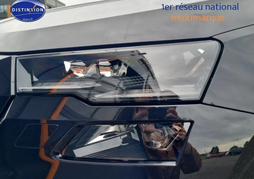 Gros plan sur le phare avant droit noir brillant du Skoda Karoq 2025 avec détails LED et reflets environnants.