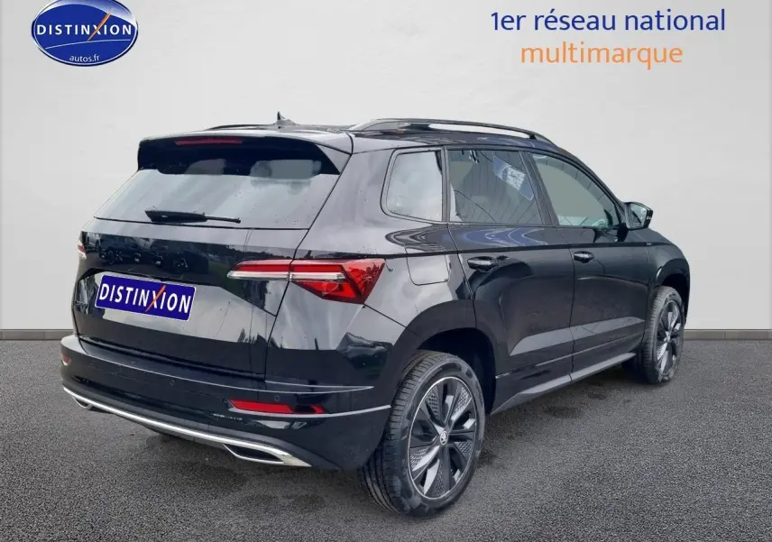 Vue 3/4 arrière droite d'un Skoda Karoq noir 2025 avec jantes alliage et barres de toit visibles.