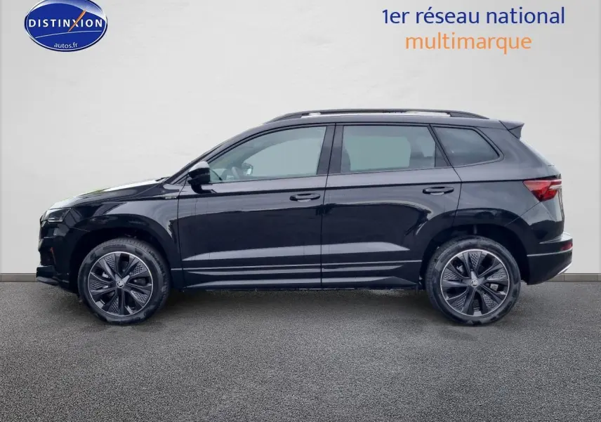 Profil côté gauche d'un Skoda Karoq noir 2025 avec jantes alu et barres de toit visibles.
