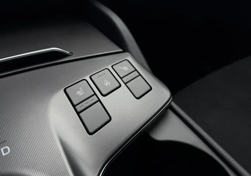 Gros plan sur les commandes de sièges chauffants et volant chauffant du KIA SPORTAGE gris Lunaire, intérieur noir.