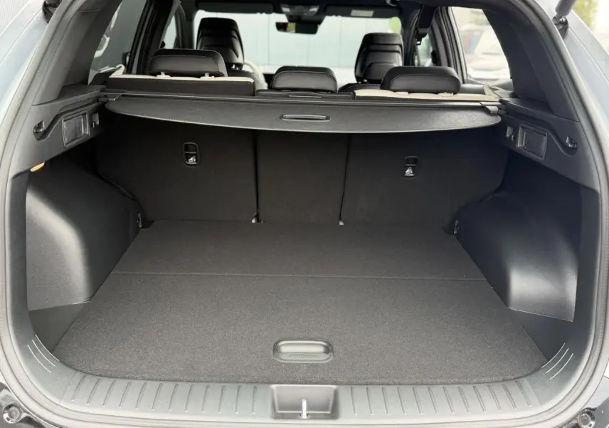 Coffre ouvert vu de l'arrière du KIA SPORTAGE gris lunaire, montrant un espace de chargement plat et couvert.