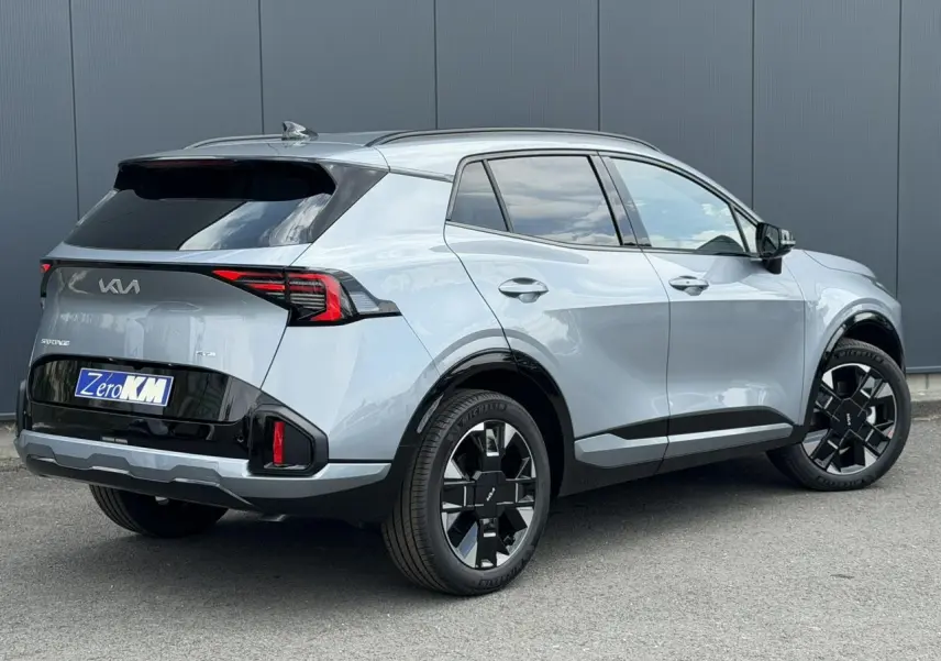 KIA SPORTAGE 2026 gris lunaire en 3/4 arrière droit, avec jantes alliage noires et feux arrière LED distinctifs.