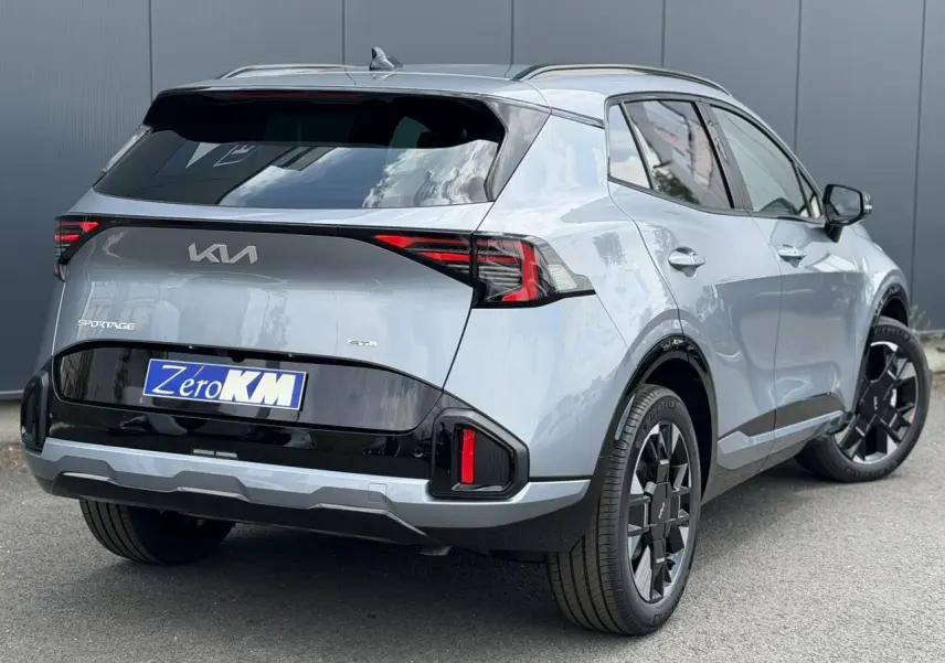 Vue 3/4 arrière droite du KIA Sportage gris lunaire 2026 avec jantes alliage noires et feux arrière LED distinctifs.