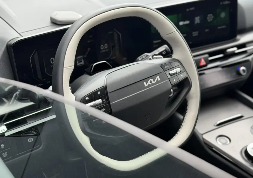 Vue rapprochée du volant bi-ton noir et gris du KIA SPORTAGE 2026 avec tableau de bord digital et écran tactile.