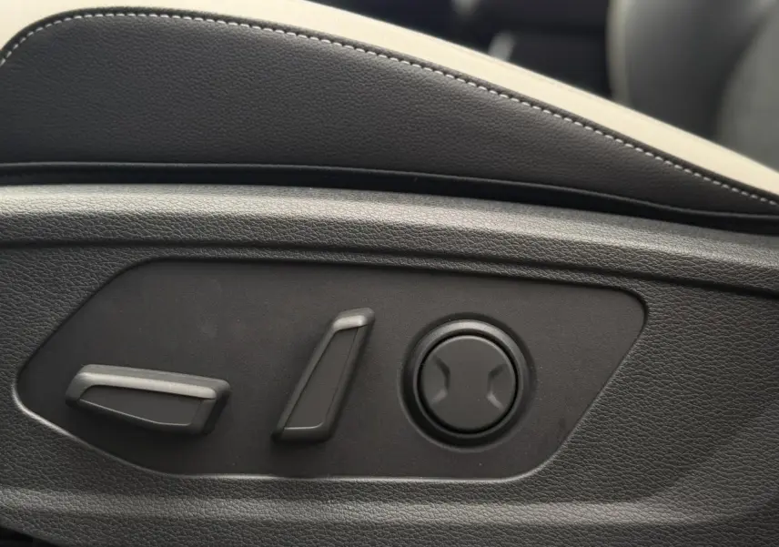 Détail des commandes électriques de réglage lombaire sur le siège avant du KIA SPORTAGE gris Lunaire.