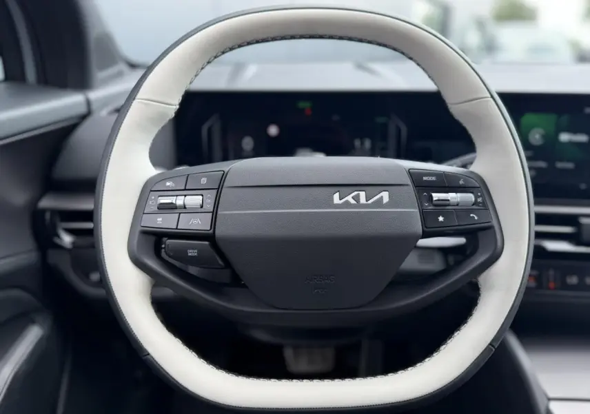 Volant bi-ton noir et blanc du Kia Sportage 2026, vue frontale centrée sur les commandes intégrées.