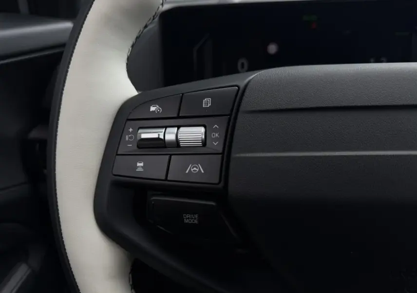 Gros plan sur les commandes gauche du volant bi-ton cuir blanc et noir du Kia Sportage 2026 gris lunaire.